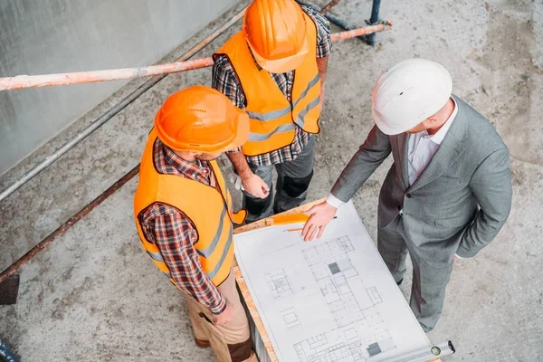 Equipo de ingenieros y arquitectos analizando planos técnicos de obra
